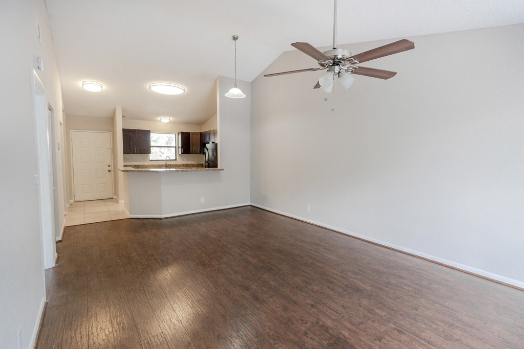 A room with a ceiling fan and wooden flooring.